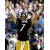 Pixelated image of a football player in black jersey with number 7 and yellow pants, standing among blurred crowd figures.