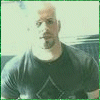 A person in a dark shirt with a diamond-shaped design stands against a light background with a green border.