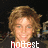 A pixelated image of a person with light brown hair and a red shirt, smiling against a dark background with text overlays.