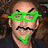 Pixelated image of a person with green glasses and mustache, surrounded by red pixelated text on white background.
