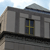 Pixelated image of a building facade with columns and a window showing a yellow cross on a dark background.