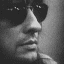 Black-and-white of 12 showing a person with dark hair and sunglasses in various poses, expressions, and angles across different frames