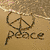 A sandy beach scene with a peace symbol drawn in the sand and the word 'peace' written below it.