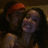 Two people in close embrace, one wearing red headband and dark clothing, the other with long dark hair; all faces blurred.