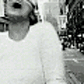 Black-and-white animated sequence showing a person in a white long-sleeve shirt performing various head and body movements against a city street background.