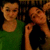 Two pixelated figures with light brown skin tones, one in green top and one in black top, positioned side-by-side against dark background.