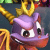 Pixelated purple cartoon character with large white eyes, black pupils, and a wide grin showing small teeth, wearing golden crown-like headpiece against dark background.