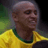 Pixelated static image of a person wearing a yellow sports jersey with green collar, visible from shoulders up against blurred background.