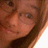 Pixelated close-up of a person's face with brown hair, visible eyes and nose, and light skin tone.