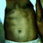 A pixelated close-up of a person's torso with visible navel, wearing light-colored clothing against a dark background.