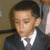 A young boy in a dark suit and purple tie appears in four showing subtle facial expression changes