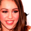 A close-up of a person with long brown hair, wearing red lipstick and visible teeth in a smile, against a white background.