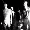 A black-and-white animated sequence showing a figure in a suit walking left to right, with a second figure following behind.