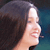 Pixelated profile view of a person with dark hair and light skin, smiling against a gradient background.