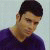 Pixelated static image of a person with short dark hair wearing a purple shirt against a light background.