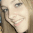 Pixelated close-up of a person's face with light skin, dark eye makeup, and a faint smile, set against a blurred background.