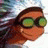 Pixelated static image of a character with long dark hair wearing green-tinted sunglasses, set against a blurred background.