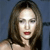 A pixelated close-up of a person with long brown hair, red lips, and a light-colored top against a blue background.