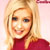 Static pixelated image of a person with long blonde hair wearing a red top against a light pink background.