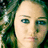 Pixelated close-up of a person's face with light skin, dark green hair, and blue eyes against a dark green background.