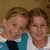 Two people in a close pose with one arm around the other, smiling at the camera.