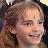 Pixelated close-up of a person with light brown hair and a neutral expression, cropped to show only the upper face and shoulders.