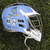 Light blue football helmet with white facemask and dark face opening, featuring '09' and '08' numerals on side, set against dark green background.