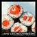 Six sushi rolls with orange fish toppings arranged in a grid on a light background, each roll wrapped in white rice and dark seaweed.