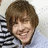 Pixelated close-up of a person with brown hair wearing a black and white striped shirt against a light background.