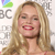 A pixelated image shows a smiling person with long blonde hair, red lips, and a light-colored top, with partial text and a colorful logo in the background.