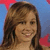 Pixelated portrait of a person with long brown hair against a blue and red background, static image with no visible text or props.