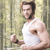 A pixelated figure in a white tank top stands against a blurred greenish background, holding a small object in one hand.