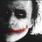 A pixelated image of a character with white face paint, dark eye makeup, and red lips in a wide smile.