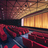 Pixelated image of a theater interior with red seats, a dark stage area, and warm yellow lighting on the upper walls.