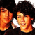 Two individuals with dark curly hair, one in a black shirt, positioned side-by-side with varying facial expressions across frames.