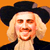 Pixelated portrait of a person with light-colored hair wearing a dark wide-brimmed hat against an orange background.