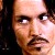 Pixelated close-up of a person's face with visible eyes, nose, mouth, and dark hair against a dark background.