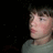 Pixelated close-up of a person's face in profile against a dark background, wearing a light-colored shirt.
