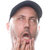 Pixelated close-up of a person wearing a dark cap, with hands near the chin and mouth, against a white background.