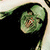 Green-skinned zombie head with dark hair, visible teeth, and red eyes against a light background.