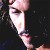 Pixelated close-up of a person's face in profile, showing closed eyes, dark hair, and a dark background with subtle color variations.