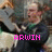 A pixelated image of a person in a dark jacket with a green collar, holding a white object, with pink text below.