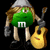 Green M&M character with brown hair, silver helmet, gray gloves, and black shoes holding a yellow acoustic guitar against a black background.