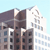 Pixelated image of a multi-story building with dark brown and white facades under a light blue sky.