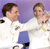 Two pixelated figures in white shirts and blue pants stand side-by-side against a purple background, with one figure extending an arm toward the other.