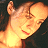 Pixelated close-up of a person's face with closed eyes, smiling mouth, and light brown hair against a dark background.