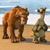 Two pixelated animals stand on a sandy beach with a blue sky and water in the background.