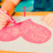 A pink heart-shaped object with text changes across frames, set against a blurred background of blue and orange tones.