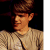 Pixelated static image of a person wearing a brown hat and light-colored shirt against dark background.