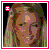 Pixelated image of a smiling woman with long light brown hair, framed by pink border with white inner line and small 'I' icon in top-left corner.